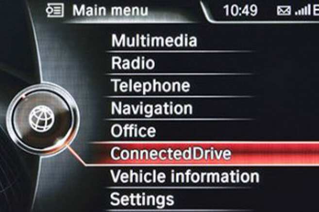 Car infotainment system main menu screen highlighting ConnectedDrive with options for multimedia, radio, navigation, and settings.