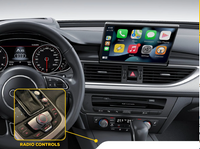 Car dashboard displaying multimedia touchscreen with app icons and highlighted radio control knob near gear shift in Audi interior